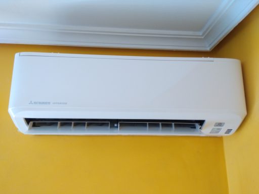 Aire acondicionado montado en la pared de una habitación con pared amarilla.
