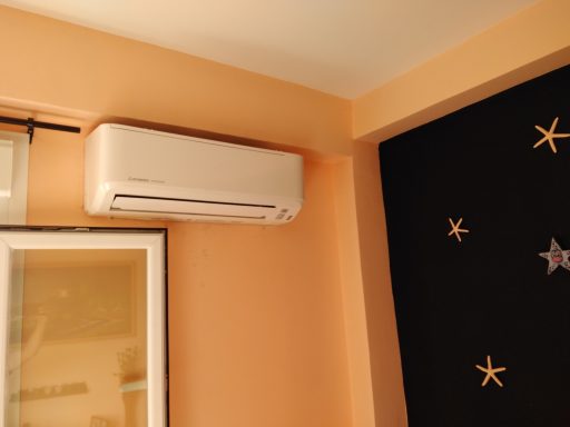 Aire acondicionado montado en la pared de una habitación con paredes de color melocotón.